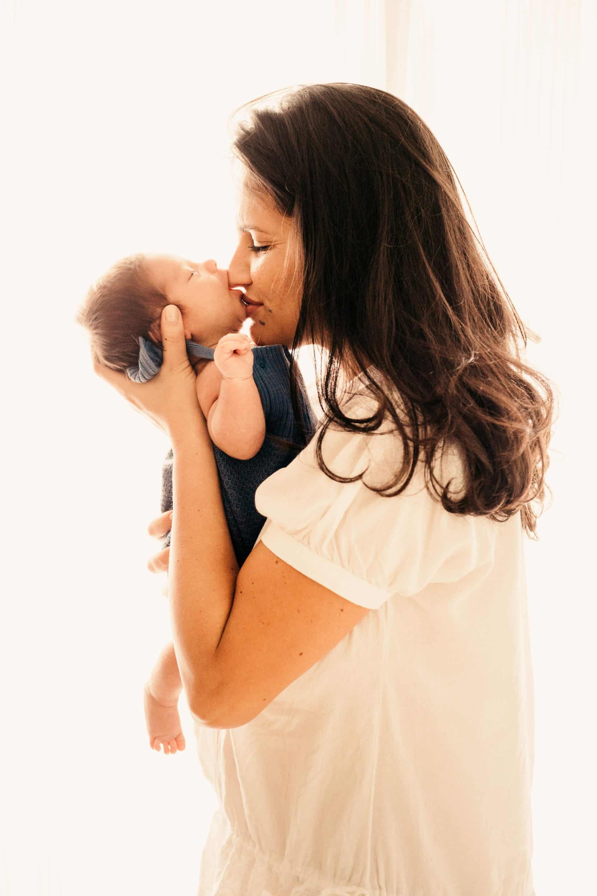 maman bisous bébé maman tenant son bébé dans les bas lui faisant un bisous