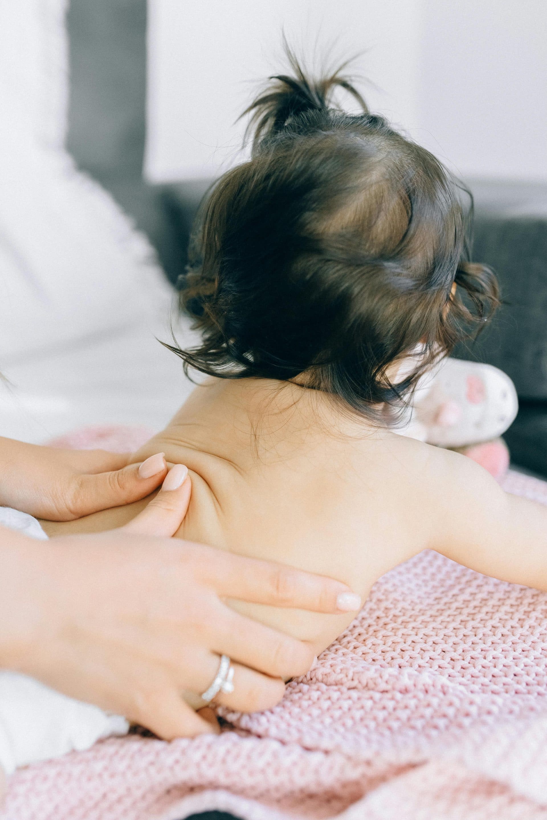 Massage bébé dos bébé allongé sur le ventre entrain de se faire massage par une accompagnante en périnatalité