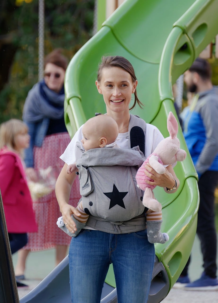 mère qui porte son bébé en porte bébé maman au parc qui porte son bébé